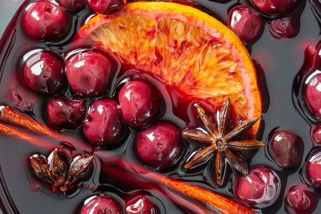 Mulled red cherry wine or punch with slice of orange and anise star and cinnamon, close up, top view, rotation. Christmas beverage.の写真素材