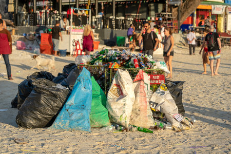 KOH PHANGAN, THAILAND - FEBRUARY 21, 2019: Rubbish on a sandy beach near the sea after a Full Moon party in island Koh Phangan, Thailandのeditorial素材
