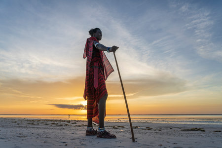 Zanzibar, Tanzania - december 07, 2019: African man masai dressed in traditional clothes on the sand beach during sunset of Zanzibar island, Tanzania, East Africa, close upのeditorial素材