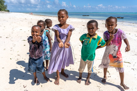 Zanzibar, Tanzania - December 01, 2019: A group of African children begs money from tourists on a sandy beach near the sea on the island of Zanzibar, Tanzania, east Africaのeditorial素材
