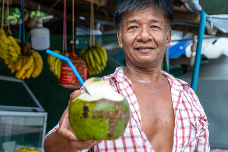 Koh Phangan, Thailand - january 23, 2020: Asian man sells fresh coconut on the street market near beach at tropical island Koh Phangan, Thailandのeditorial素材