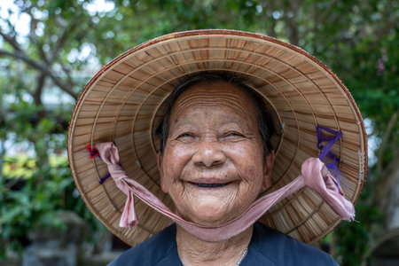 Danang, Vietnam - June 30, 2020: Ethnic old woman in straw hat on a street market of Danang, Vietnamのeditorial素材