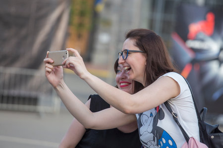 Kiev, Ukraine - may 05, 2018: Two happy girls take pictures of themselves on a smartphone during the Ethno festival on the street of Kiev, Ukraineのeditorial素材
