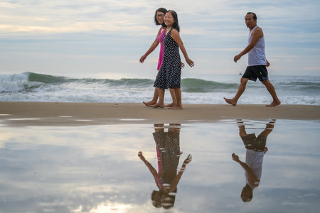 Danang, Vietnam - June 15, 2020: Vietnamese two women and man on the beach near sea in the morning on the city Danang, Vietnam. Local people relax on the beachのeditorial素材