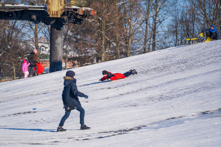 Shepetivka, Ukraine - january 21, 2021: Children sledding with mountain warm winter day. Ukrainian children having fun on snowy small mountain during the winter in Shepetivka, Ukraineのeditorial素材