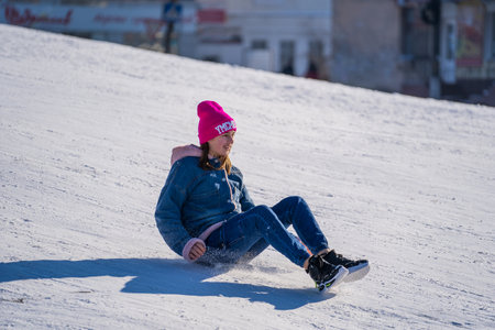 Shepetivka, Ukraine - january 21, 2021: Children sledding with mountain warm winter day. Ukrainian children having fun on snowy small mountain during the winter in Shepetivka, Ukraineのeditorial素材