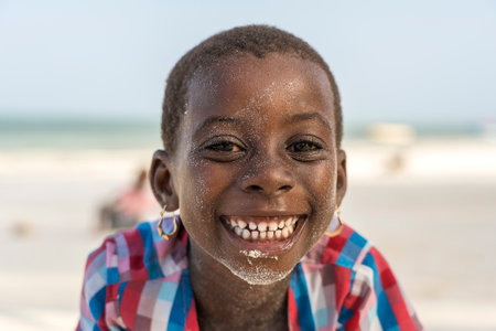 Zanzibar, Tanzania - january 15, 2020: Young African girl on a tropical beach near sea on the island...