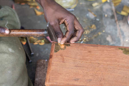 African man hammer a nail into a wooden box on the street on the island of Zanzibar, Tanzania, East Africa, close upの写真素材