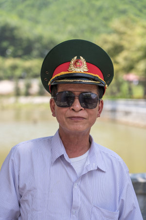 Danang, Vietnam - june 27, 2020: Vietnamese old happy man with military hat on his head and sunglasses on the street in city Da Nang, Vietnamのeditorial素材