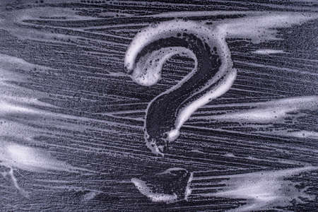 Question mark made from soap foam on a black background. Abstract foam texture on black background....