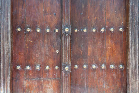 Close up of a ancient traditional wooden carved door with ornaments and bronze spike in Stone Town on island Zanzibar, Tanzania, East Africaの写真素材