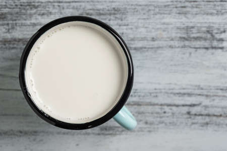 White milk in a metal mug on a white wooden background, close up, top view. Dairy product concept, copy spaceの写真素材
