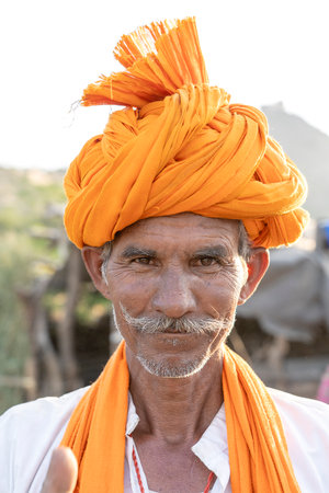 PUSHKAR, INDIA - NOVEMBER 13, 2018: Indian man in the desert Thar during Pushkar Camel Mela near holy city Pushkar, Rajasthan, India. This fair is the largest camel trading fair in the world.のeditorial素材