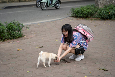 Hanoi, Vietnam - march 01, 2020: Beautiful Vietnamese girl gives water to the dog from her hands on the street in the old town of Hanoi, Vietnamのeditorial素材