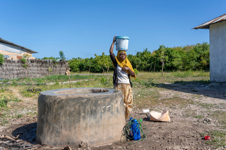 Zanzibar, Tanzania - january 14, 2020: Unidentified african girl and bucket with water on a street in Zanzibar Island, Tanzania, East Africaのeditorial素材