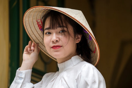 Hanoi, Vietnam - march 01, 2020: Beautiful Vietnamese woman in straw hat on the street in the old town of Hanoi, Vietnamのeditorial素材