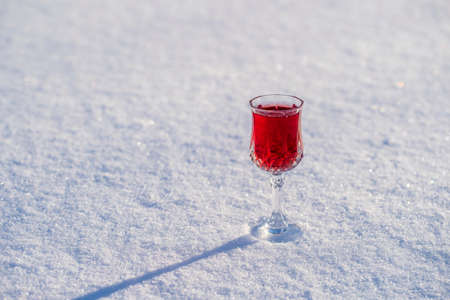 Homemade tincture of red cherry in a wine crystal glass on a snow and white background, Ukraine, close up. Berry alcoholic drinks conceptの写真素材