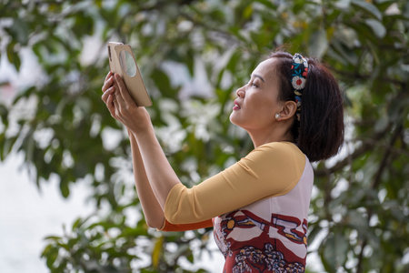 Hanoi, Vietnam - March 01, 2020: Vietnamese woman takes a photo on a smartphone in the center of Hanoi, Vietnamのeditorial素材