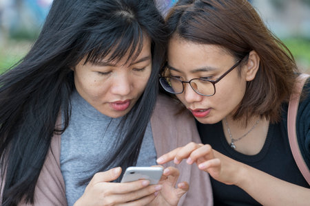 Hanoi, Vietnam - march 01, 2020: Two Vietnamese girls look at photos on a smartphone in the center of Hanoi, Vietnamのeditorial素材