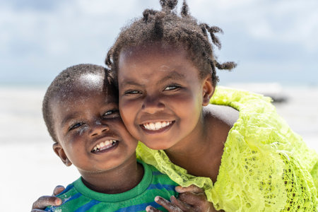 Zanzibar, Tanzania - December 12, 2019: Young happy African girl and boy near sea water on the tropical beach in island of Zanzibar, Tanzania, east Africa, close upのeditorial素材