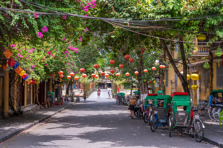 Hoi An, Vietnam - july 01, 2020: Colorful street full of paper lanterns and green tropical trees near river in Hoi An town, Vietnamのeditorial素材