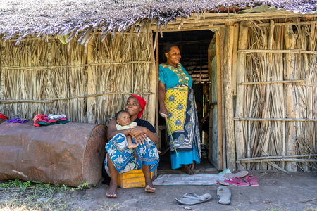 Zanzibar, Tanzania - December 13, 2019: African family near a straw house on a street of Zanzibar, Tanzania, East Africaのeditorial素材