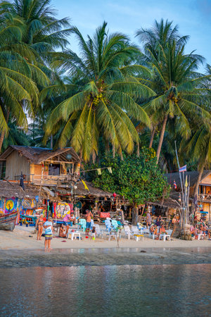 Koh Phangan, Thailand - february 06, 2020: Beach bar, coconut palm trees, sea water and rest people during sunset at tropical island Koh Phangan, Thailandのeditorial素材