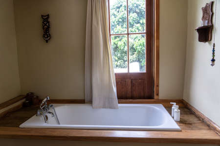 Comfortable white bath in bathroom near the window in the attic house, Tanzania, East Africa, close...
