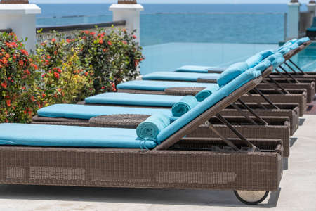 Close up of towels on lounge chairs near a luxury swimming pool at a tropical resort spa in island...