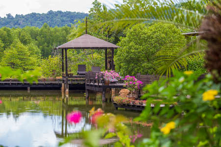 Wooden gazebo with sun loungers for relaxing on a terrace with flowers next to a lake on the tropical island of Thailand. Nature and travel conceptの写真素材