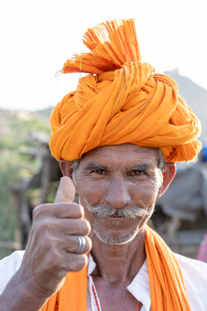 PUSHKAR, INDIA - NOVEMBER 13, 2018: Indian man in the desert Thar during Pushkar Camel Mela near holy city Pushkar, Rajasthan, India. This fair is the largest camel trading fair in the world.のeditorial素材