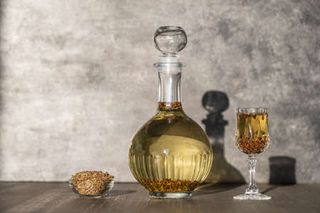 Homemade birch buds tincture in a glass bottle and a wine crystal glass on a wooden table background, Ukraine, close up. Herbal alcoholic drinks conceptの写真素材