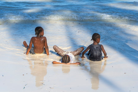 Zanzibar, Tanzania - january 10, 2020: Young African girls in sea water on a tropical beach on the island of Zanzibar, Tanzania, east Africa, close upのeditorial素材