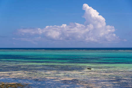 White beautiful clouds and blue sky over sea water waves on the island of Zanzibar, Tanzania, East...