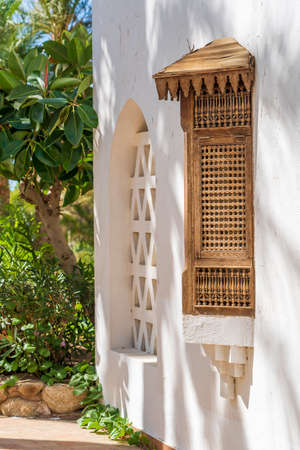 Closed window with wooden bars in an old white wall of a house on the street of Egypt in Sharm El Sheikh, close up, copy spaceの写真素材