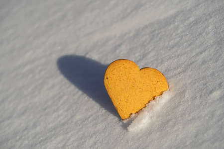 Heart shaped xmas cookie on a white snow in winter, close upの写真素材