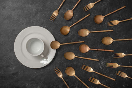 White ceramic plate, cup and brass forks and spoons look like sperm competition. Spermatozoons floating to ovule. Concept of fertilization, pregnancy and contraception. Top view, close upの写真素材