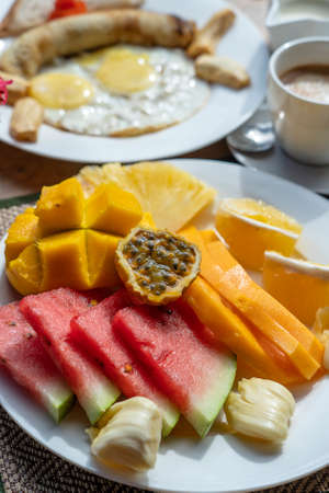 Tropical breakfast of fruit, coffee and scrambled eggs and banana pancake on the beach near sea in hotel restaurant, island Zanzibar, Tanzania, Africa, close upの写真素材