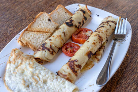 Tropical breakfast of scrambled eggs and wrapped banana pancakes in hotel restaurant, island Zanzibar, Tanzania, Africa, close up. Top viewの写真素材