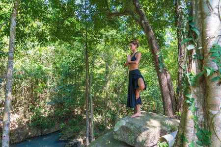 Young caucasian brunette girl is meditating in nature at tropical garden in summer, Thailand, close upの写真素材