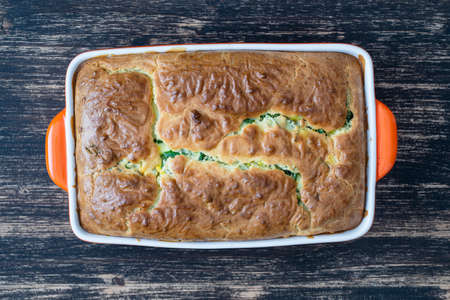 Pouring pie with green wild garlic leaves and boiled eggs on wooden table, close up, top viewの写真素材