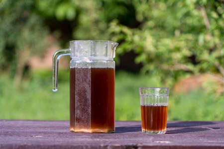 Homemade bread kvass with leaven and malt in a glass jug in garden, close up. Refreshing summer...