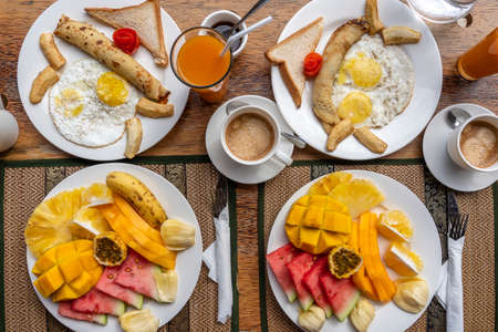 Tropical breakfast of fruit, coffee and scrambled eggs and banana pancake for two on the beach near sea in hotel restaurant, island Zanzibar, Tanzania, Africa, close upの素材 [FY310171080670]