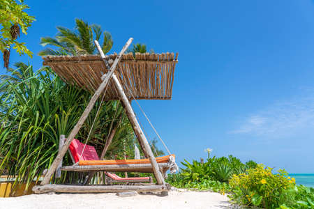 Wooden swing with a mattress under a canopy on the tropical beach near sea, island Zanzibar, Tanzania, East Africa, travel and vacation conceptの写真素材
