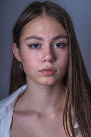 Charming young girl with freckles and blue eyes on a black background, indoors, close up portraitの写真素材