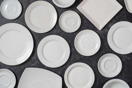 Many white empty ceramic plate on black background, close up. View from aboveの写真素材