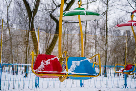 Baby swings at a playground blanketed with clean snow on a winter day in the city park, Ukraineの写真素材