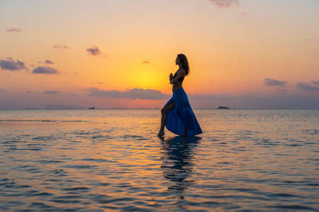 Young beauty girl dancing at tropical beach on sea water at paradise island at sunset, Thailand, close up. Summer concept. Holiday travel.の写真素材
