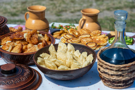 Lot of pancakes, dumplings and wine on the table in yard, close up, Ukraine. Traditional ukrainian foodの写真素材