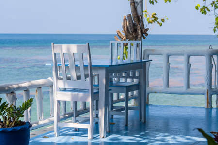 Wooden table and chairs in tropical beach cafe near blue sea water, island Koh Phangan, Thailand. Beach cafe near the sea, outdoors. travel and vacation conceptの写真素材
